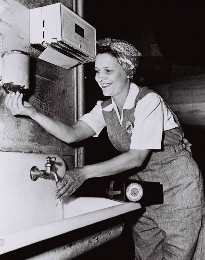 A WWII era women washes her hands before work at the factory