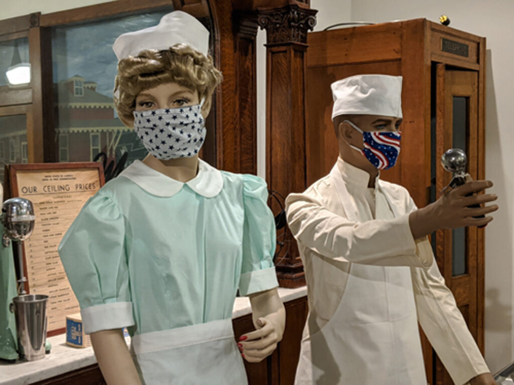 Two mannequins in display wearing cloth face masks